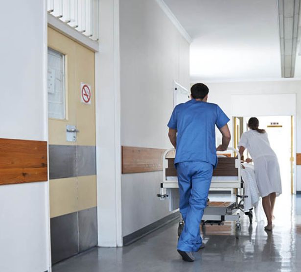 Deux soignant déplace un lit dans le couloir de l'hôpital - MACSF
